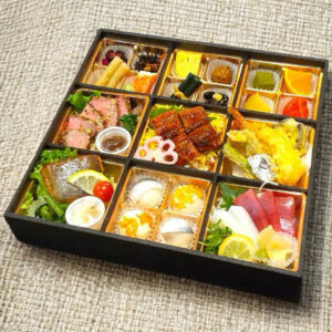 季節の食材を使った彩り豊かな和風仕出し弁当。鰻の蒲焼きや天ぷら、刺身、焼き魚、ローストビーフなど多彩な料理が一つの重箱に美しく盛り付けられている。