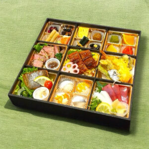 色とりどりの料理が詰め込まれた和食仕出し懐石弁当。鰻の蒲焼き、刺身、天ぷら、ローストビーフ、焼き魚など多彩なおかずと、一口サイズの寿司が美しく盛り付けられている。家族や法事の集まりにふさわしい、華やかな一折。