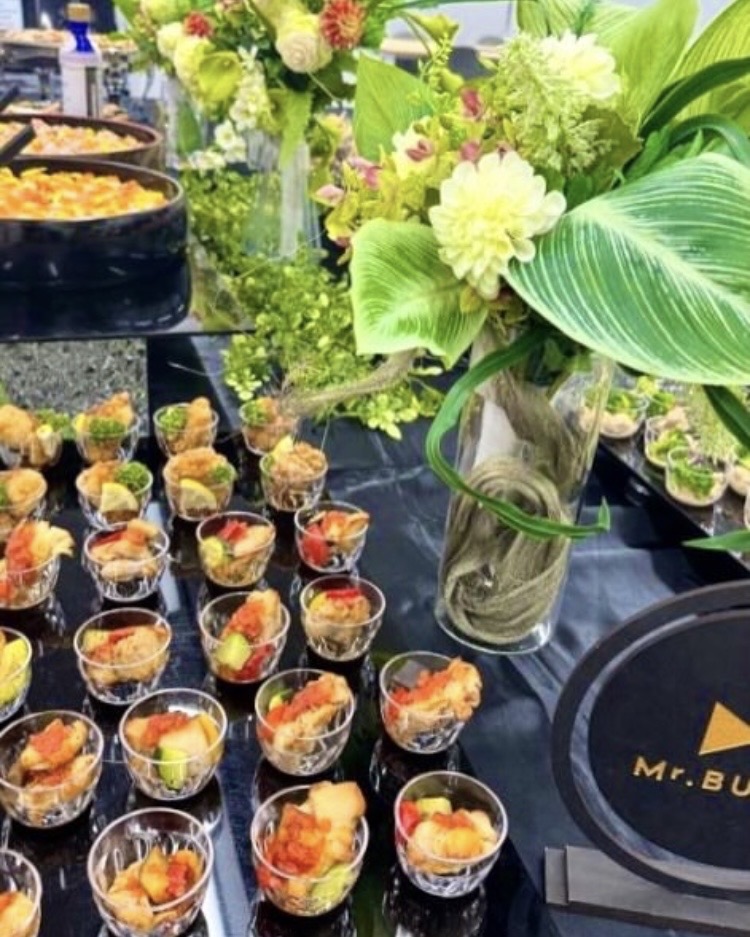 松山市で会社の懇親会ケータリングを考えるための小分け料理と装花を並べたビュッフェ台のイメージ